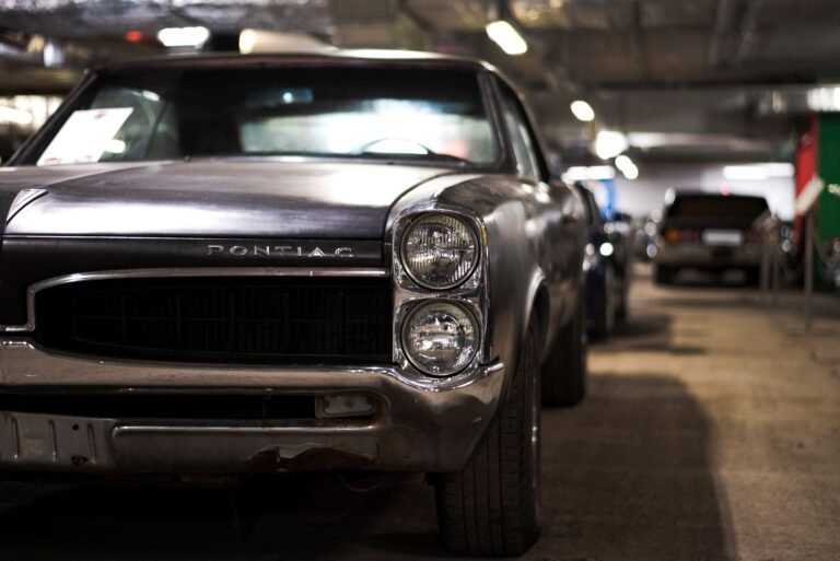 Close-up of vintage Pontiac muscle car parked indoors in an underground garage.